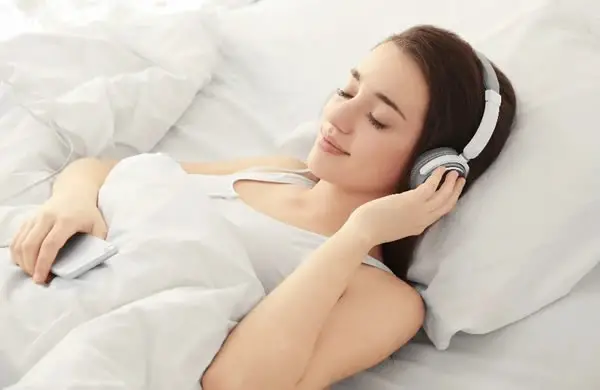 Woman listening to lucid dreaming music in bed